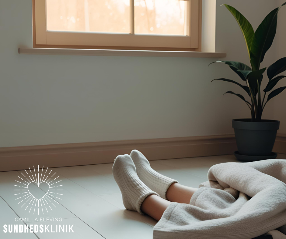 Et fredeligt rum med blødt lys og fødder hvilende på gulvet. Billedet symboliserer følelsen af at vende hjem til sig selv og finde balance uden anstrengelse.